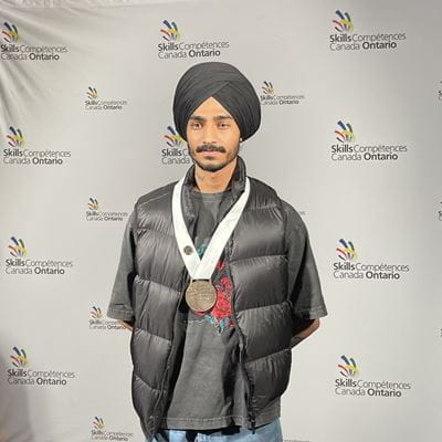 Sheridan student Sirjan Singh stands with his precision machining bronze medal around his neck