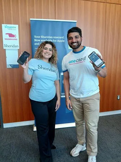 Two people hold up their cellphones displaying Sheridan's mobile onecard app
