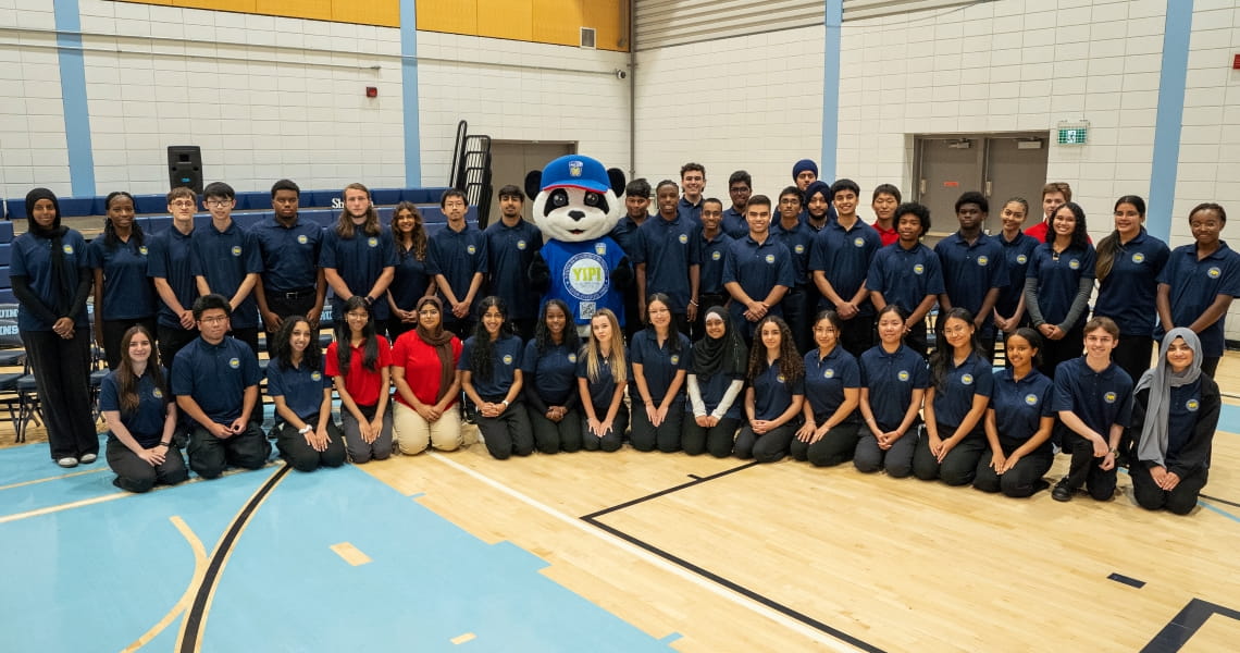 The 44 YIPI students pose with the police panda mascot in the gym