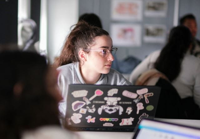 A student looks up to her left from her laptop
