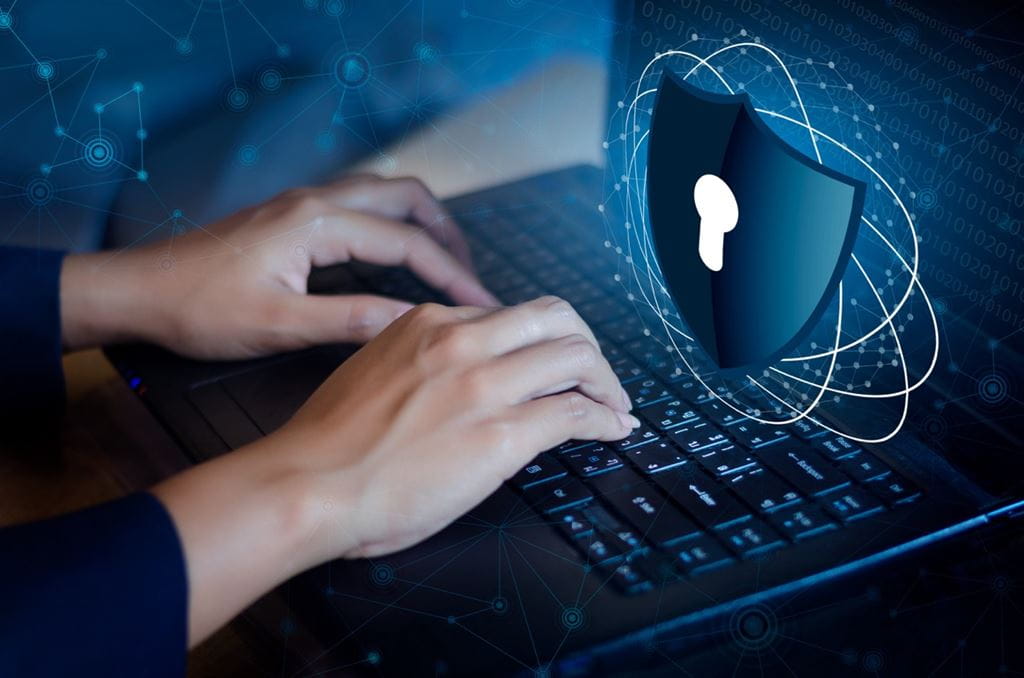 A person's hands hover over a laptop keyboard in a graphic that represents cyber security