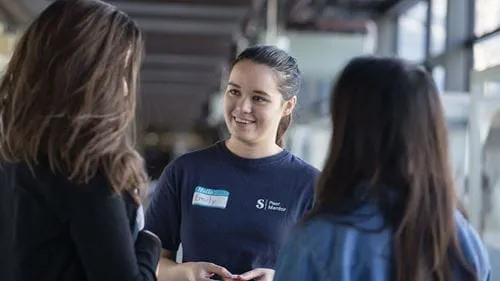 A tour guide smiles while answering a question from an Open House guest