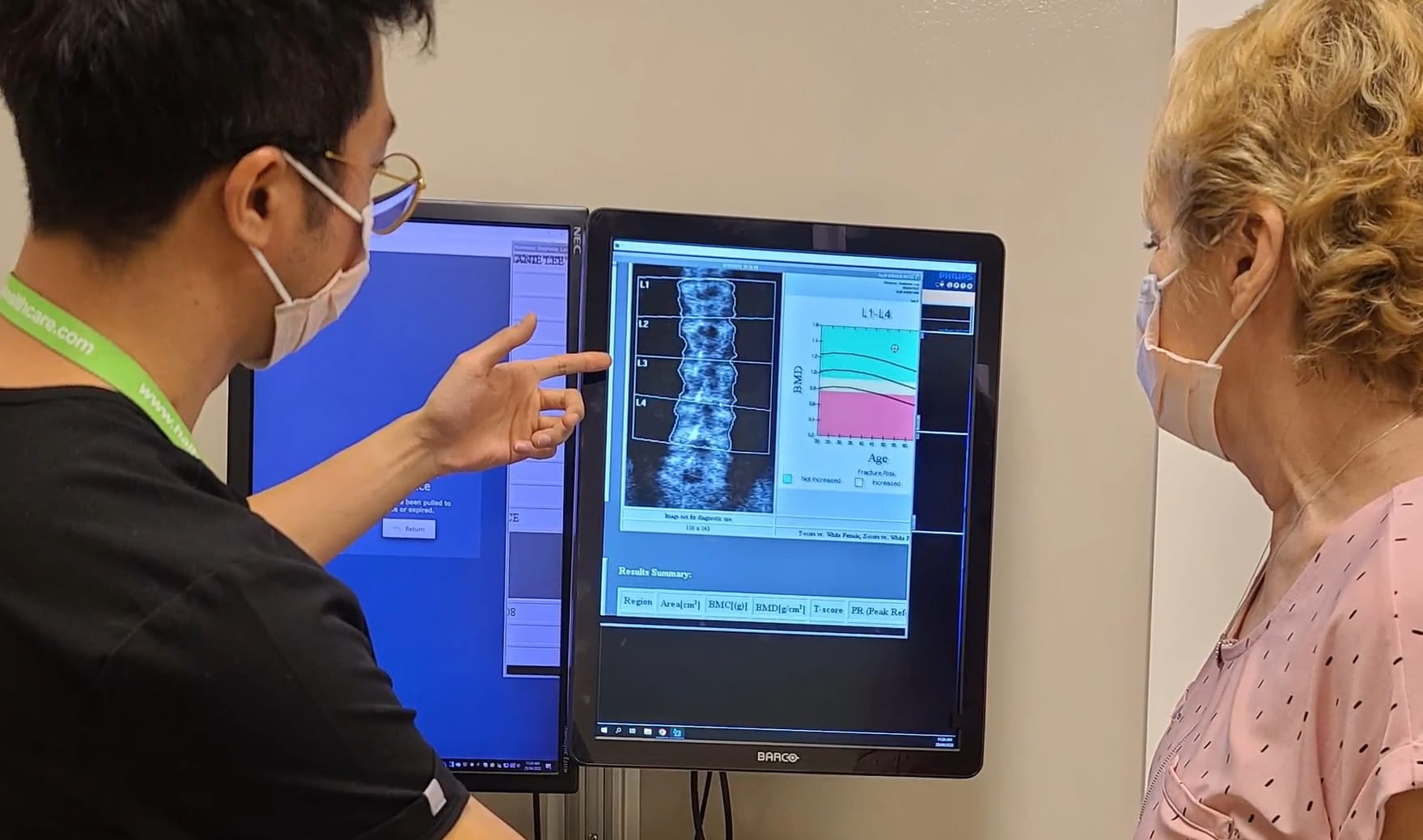 A researcher and patient look at a screen displaying osteoporosis imaging