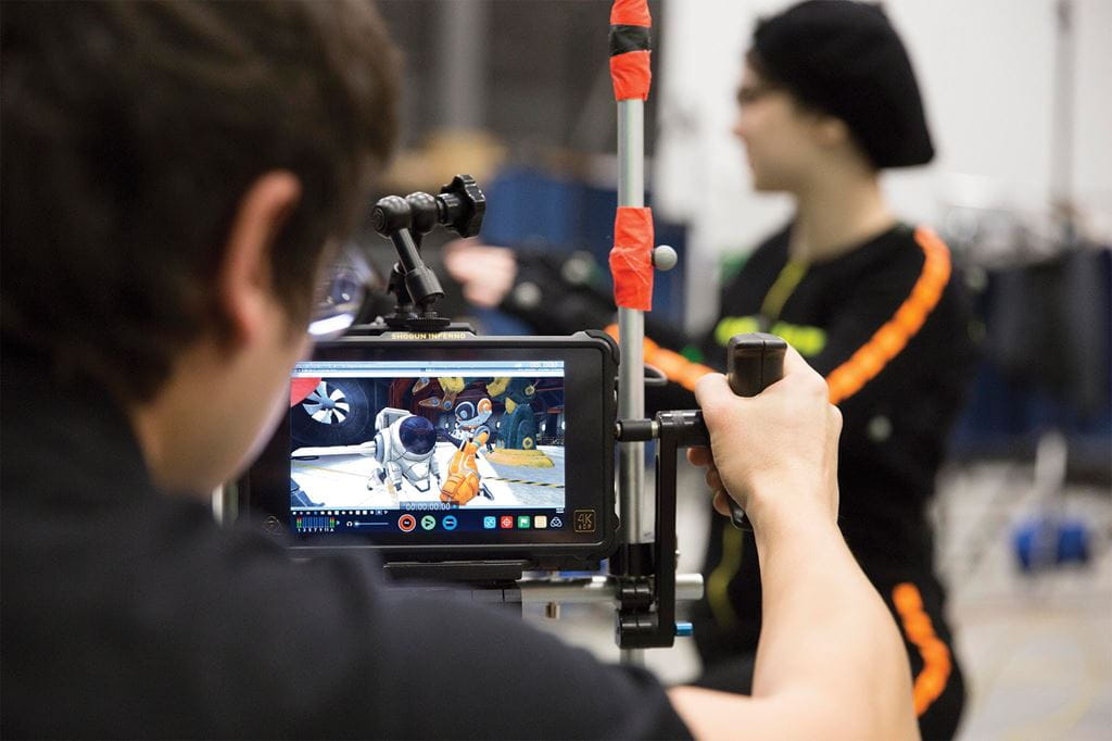 A camera person looks at their screen that depicts an animated scene