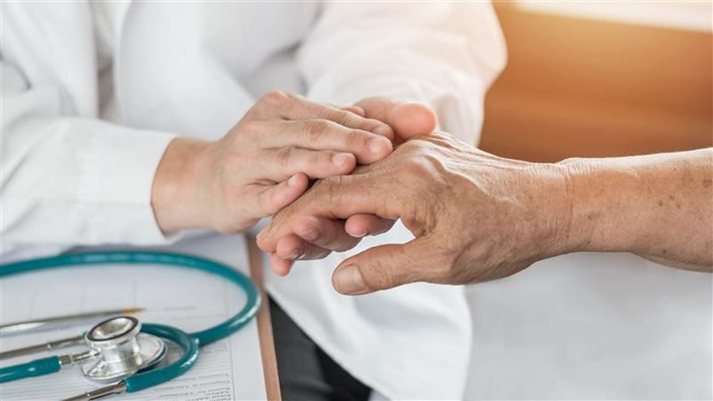 A social worker holding an elderly hand. 