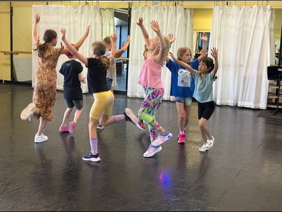 Campers at theatre camp dance as they move together in a circle.