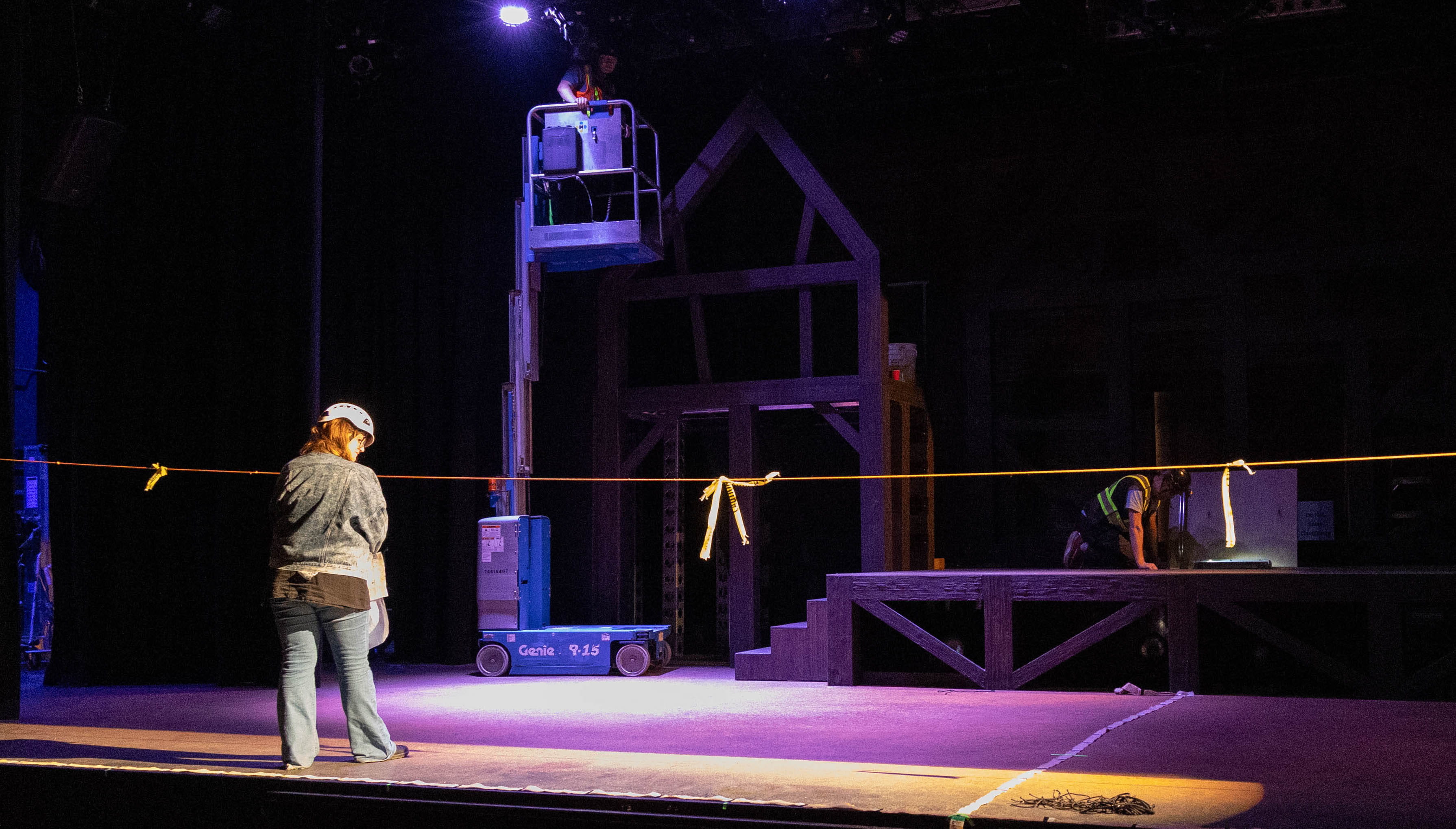 A technical student stands on a theatre stage as it's being built.