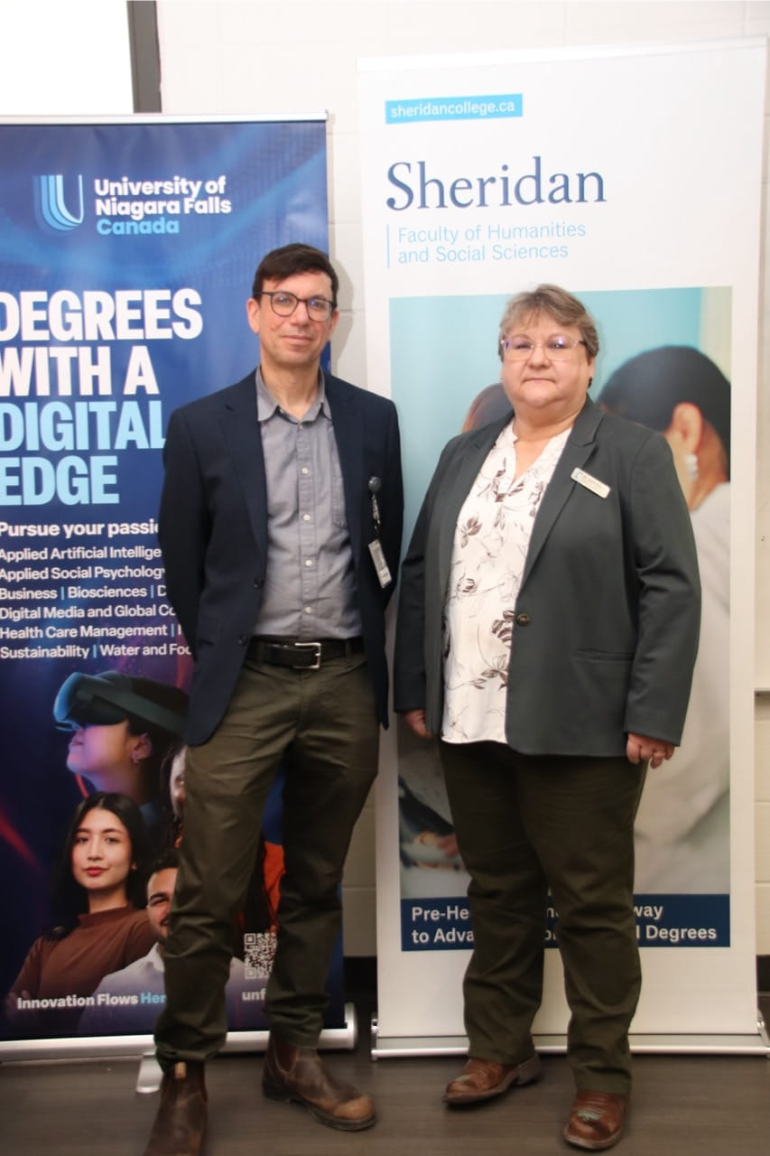 Sheridan administrator Gabriel Levine and University of Niagara Falls Canada administrator Janine Gray stand side by side in front of signage representing the two institutions.