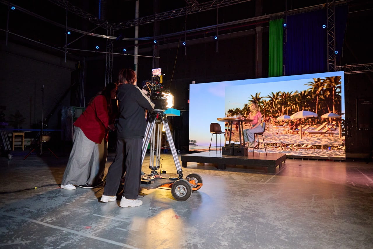 A virtual production set picturing a person in front of a beach backdrop
