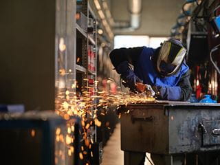 Sparks fly as a person stands at a table operating a metal grinder