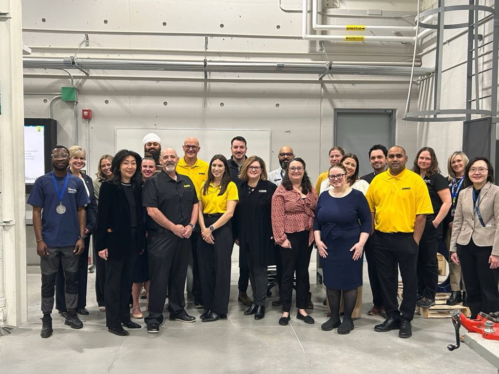Representatives from Sheridan and DEWALT gather for a group photo inside a large room at Sheridan's Magna Skilled Trades Centre 