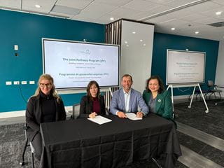 Representatives of 911³Ô¹ÏÍø and Languages Canada are seated behind a table after signing a partnership agreement