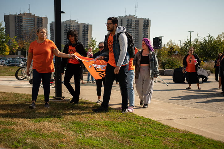 Sheridan Indigenous students wearing orange shirts carrying the Every Child Matters flag