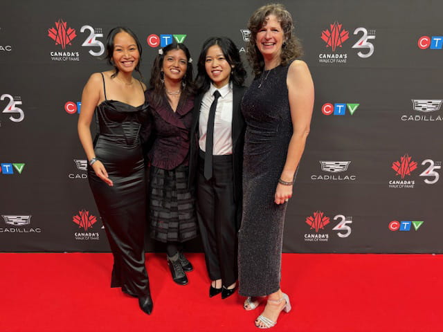Four people posing side-by-side while standing on a red carpet.