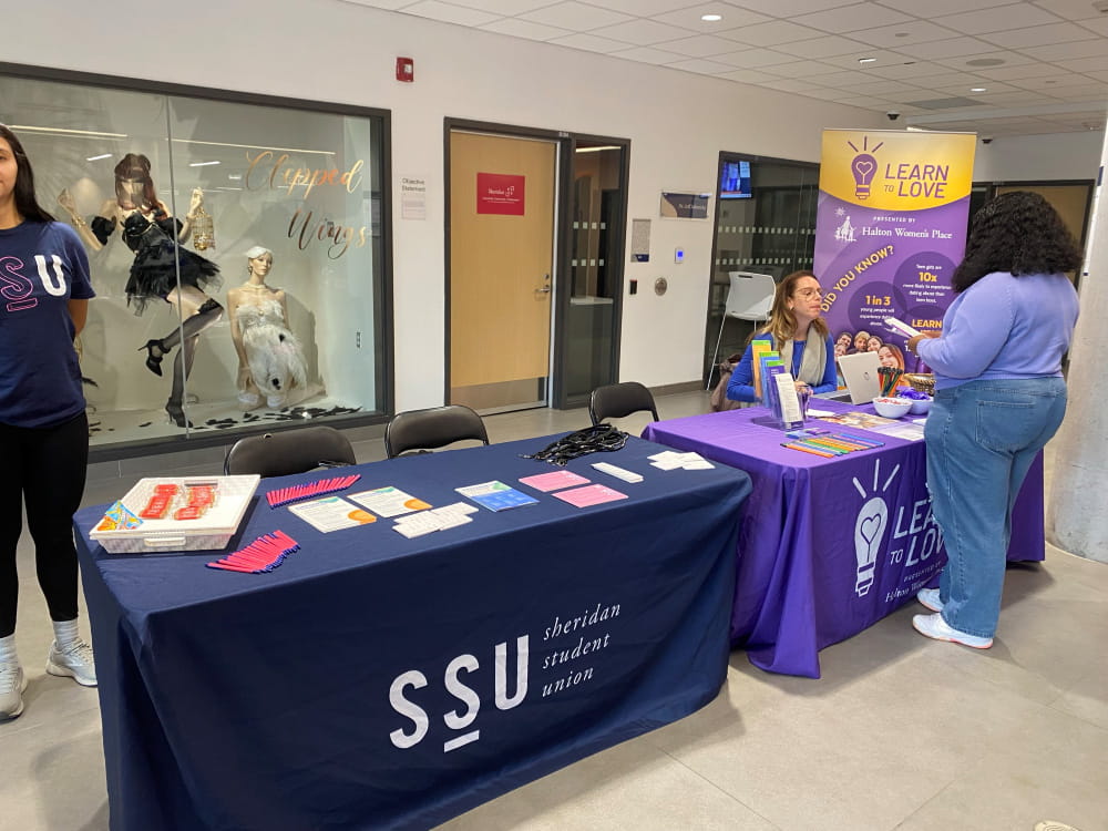 Marketplace tables at HMC campus. Two people interact.
