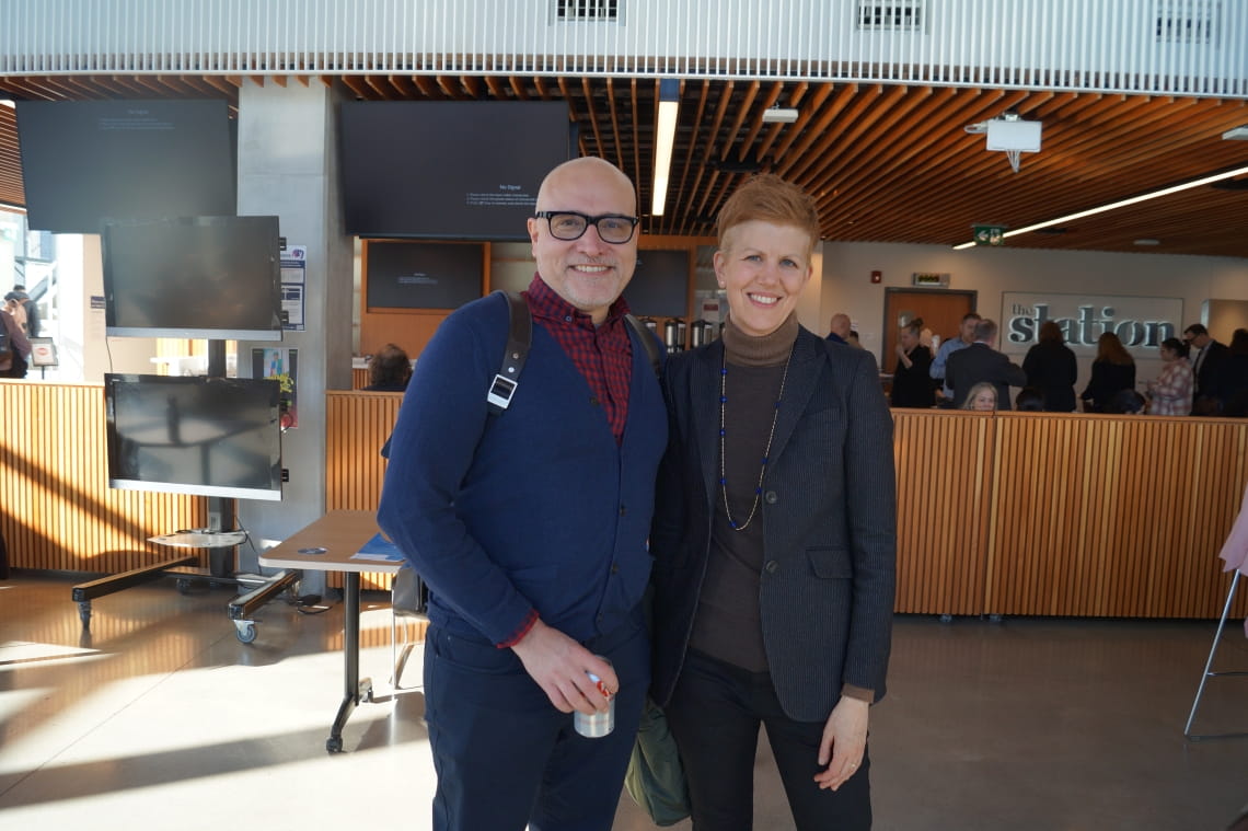 Two people smile at the camera in the HMC atrium
