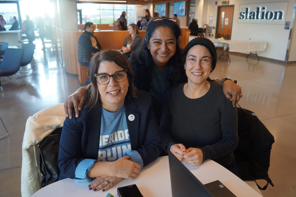Three people at a table smile for the camera