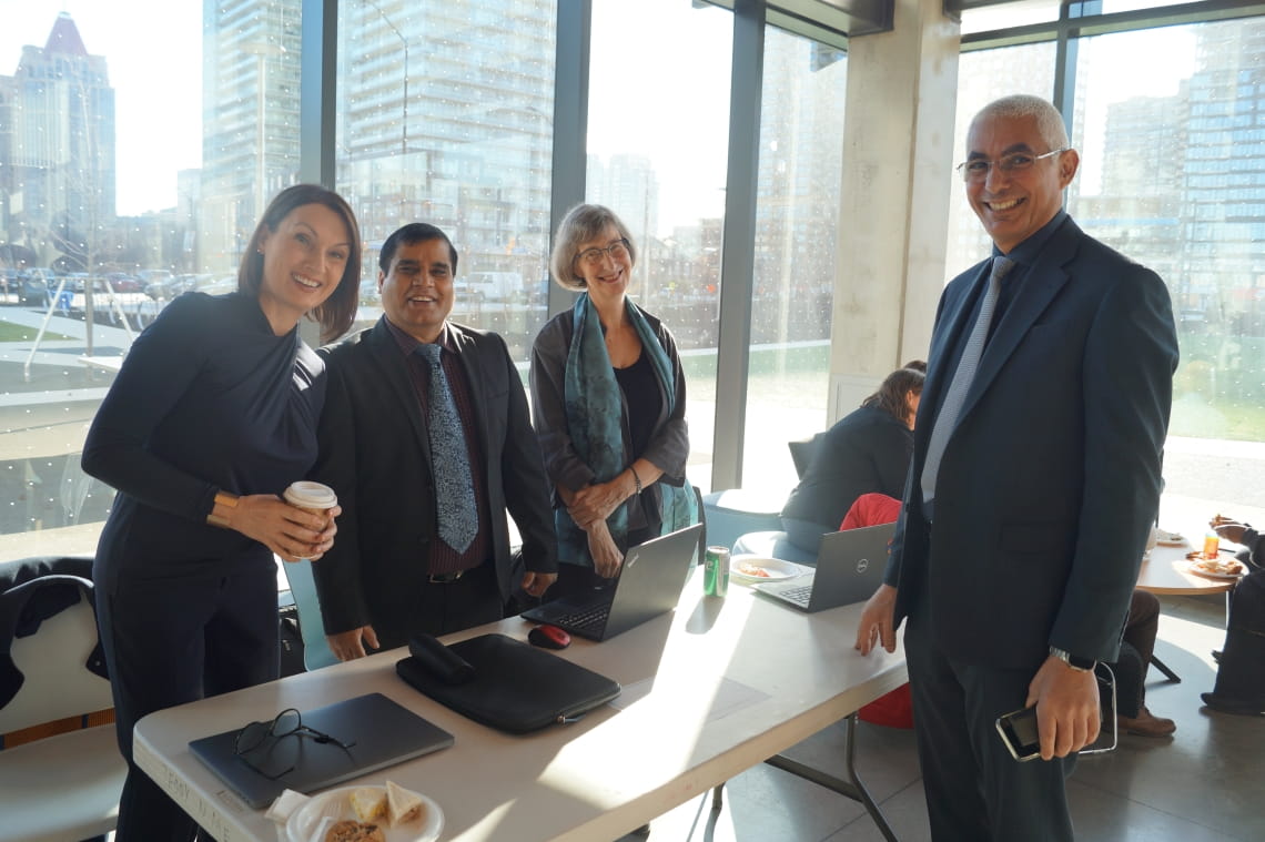Four people stand around a table and smile for the camera