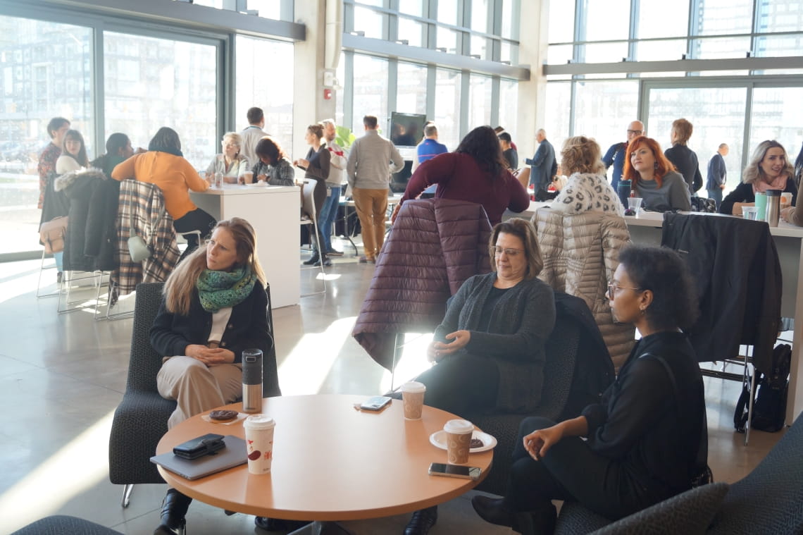 People are gathered around tables having conversation in the HMC atrium