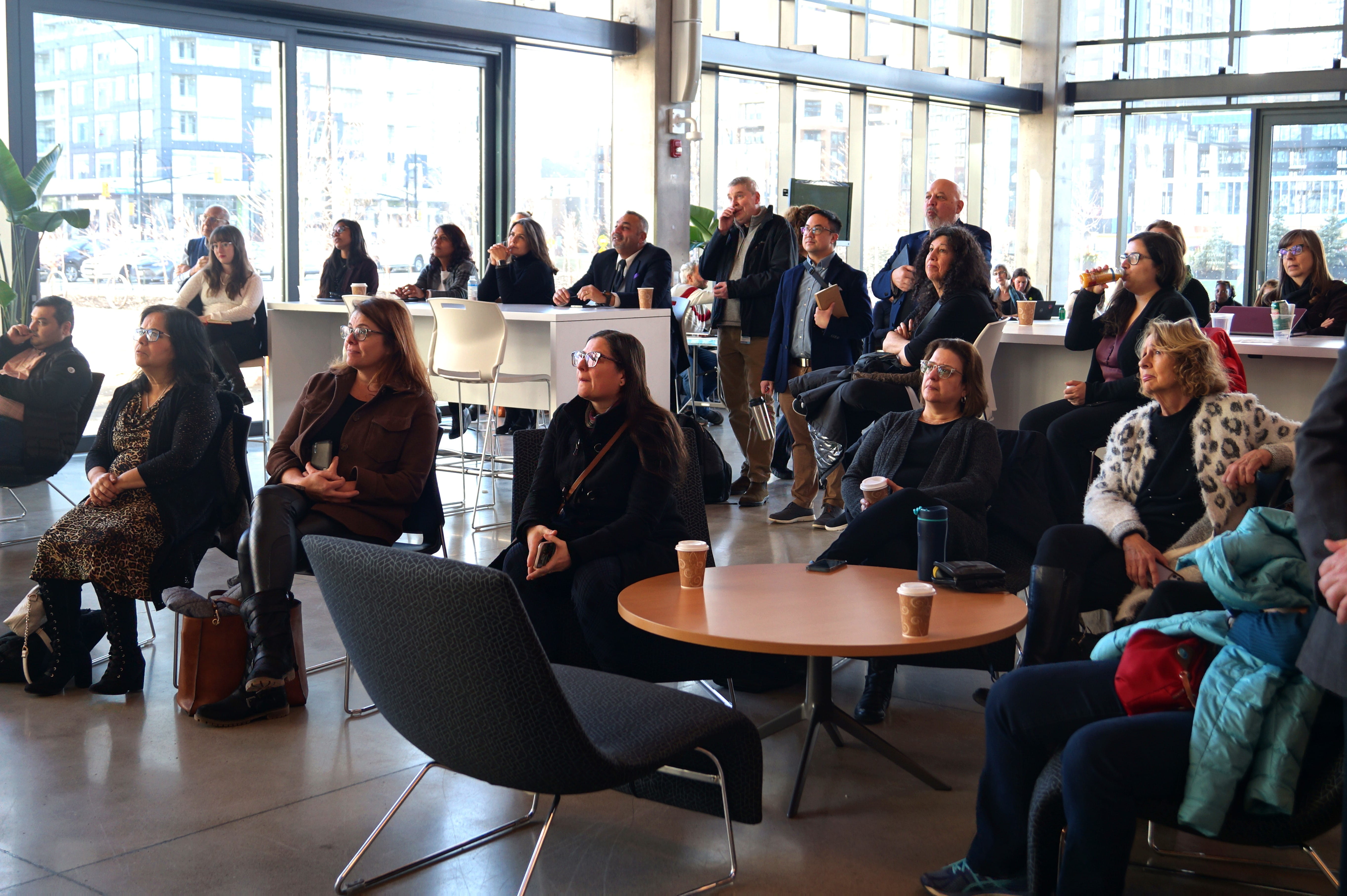 Faculty sitting at tables listen to a speaker