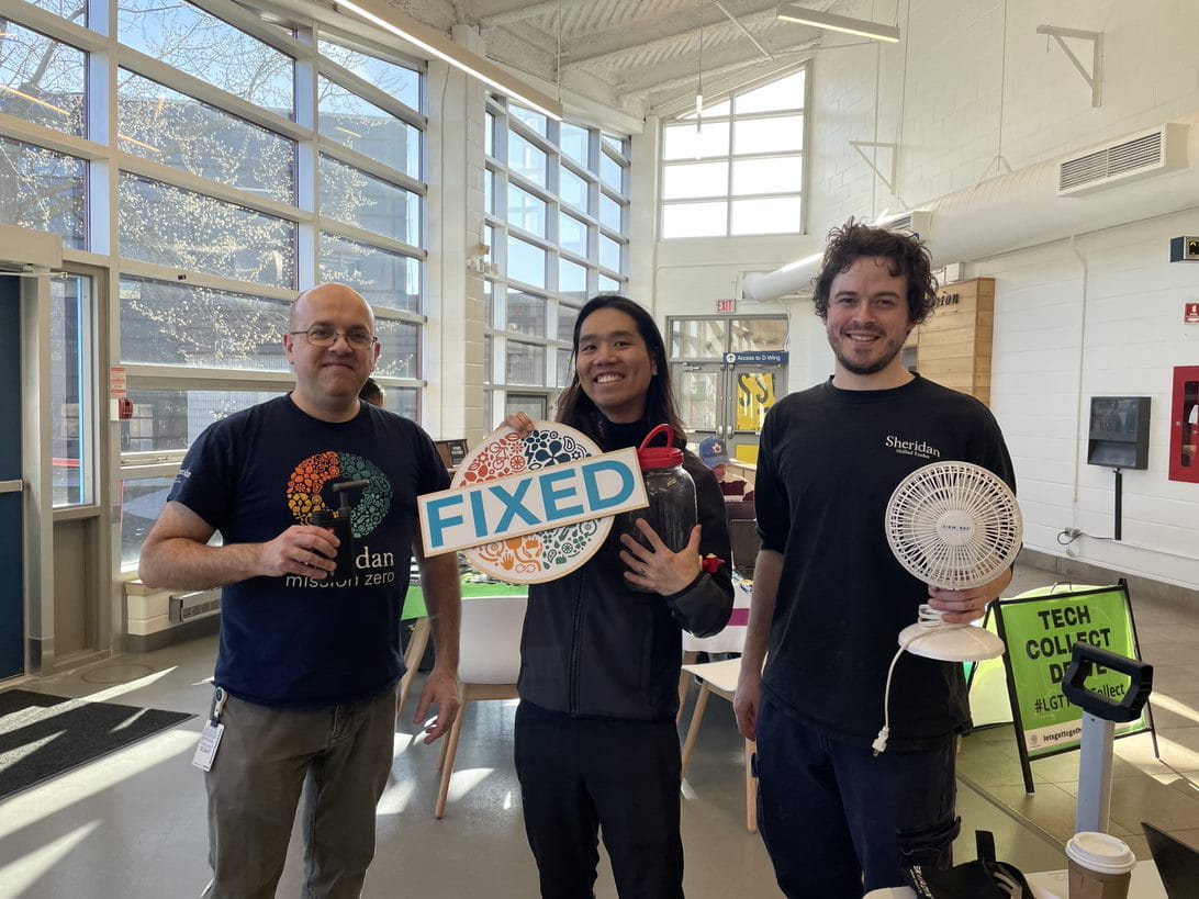 Three people hold items fixed at the repair cafe