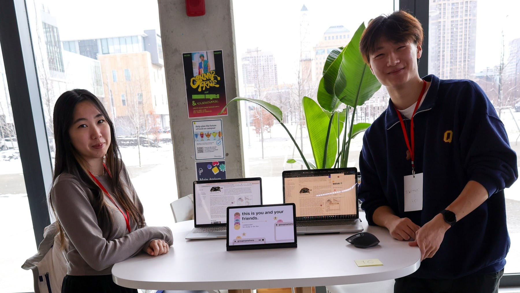 Two students stand at a table with a tablet on it.