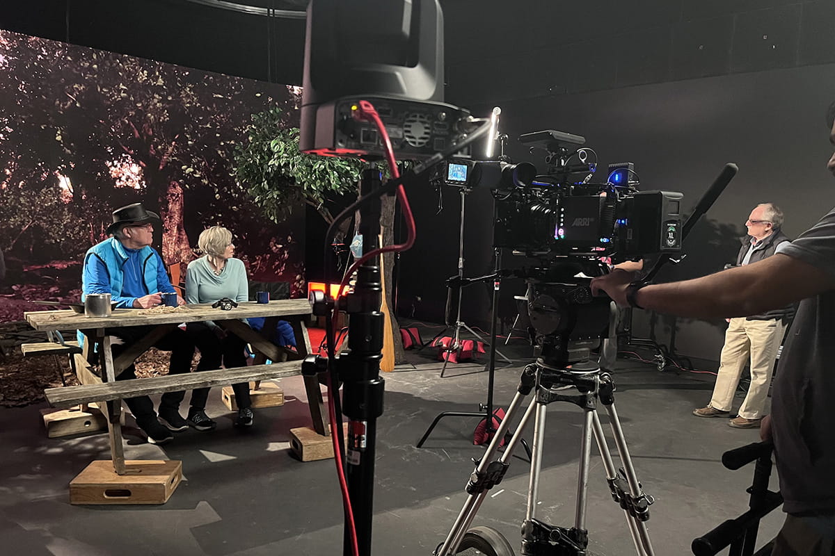 Two people seated at a picnic table on a production stage