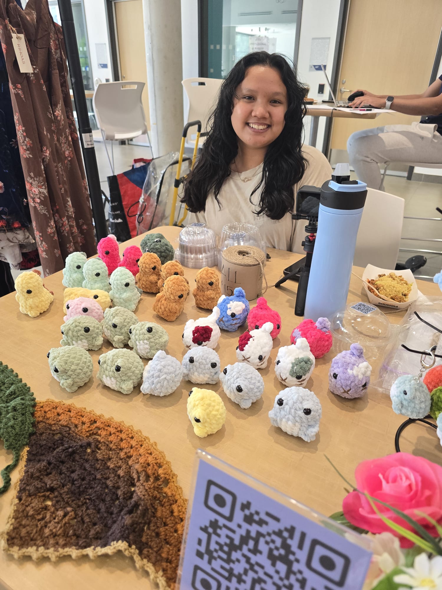 Architectural Technology student Kate Panares sits behind a table that displays her homemade crochet plushies and keychains