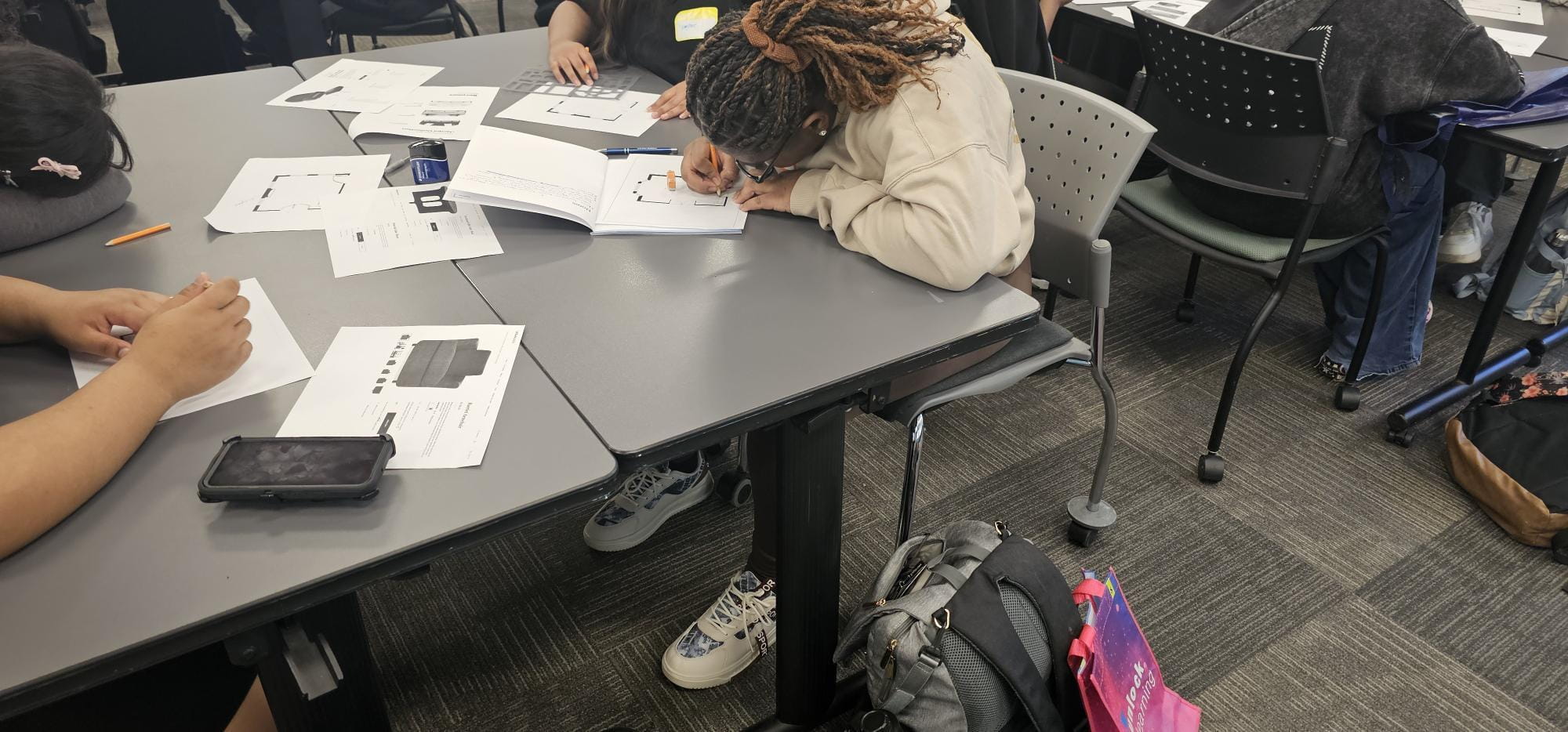Students sit at a table to complete an interior design project