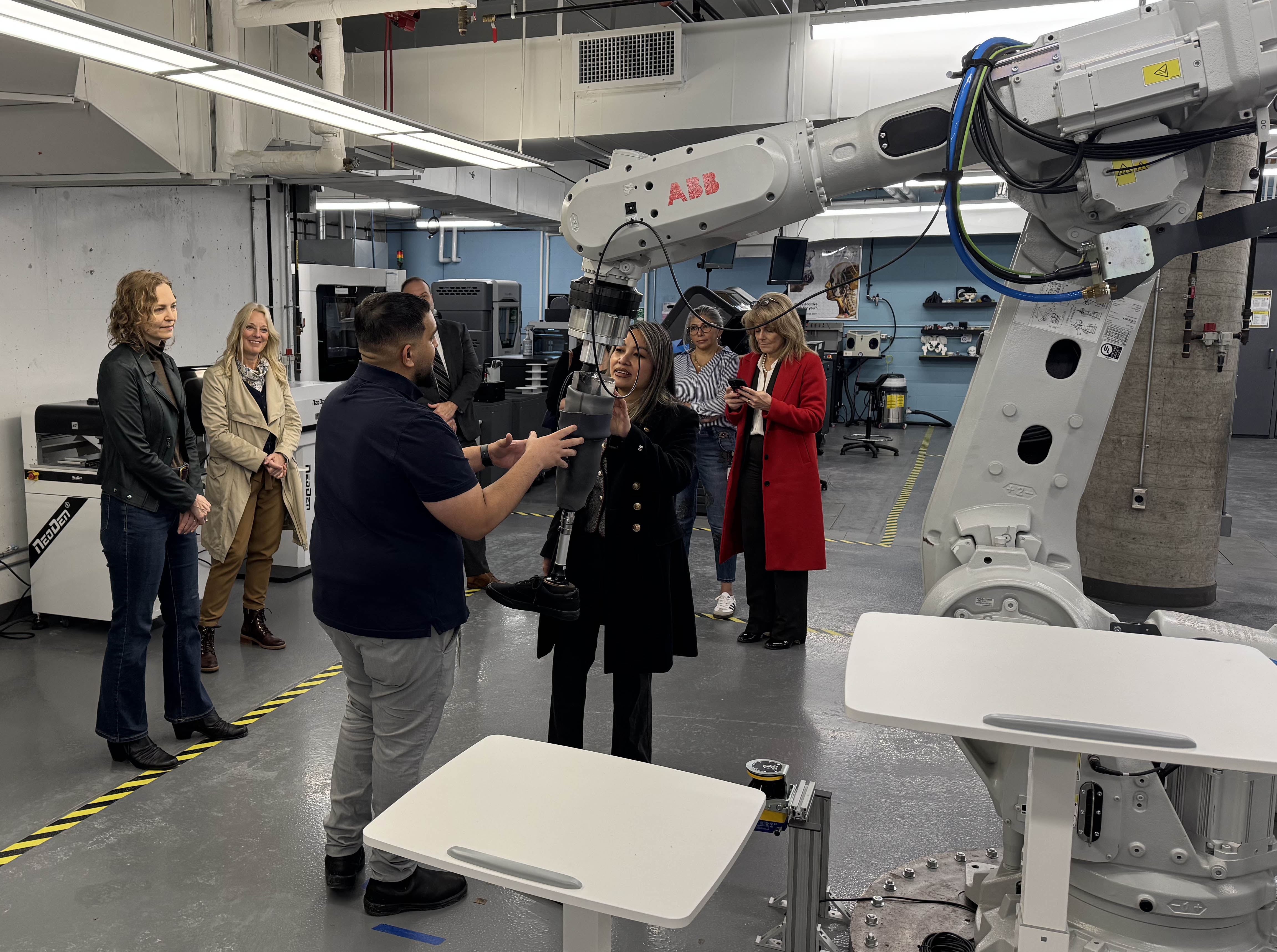 Representatives of Osler Research Institute for Health Innovation look at a prosthetic gait simulator during a tour of Sheridan's Centre for Intelligent Manufacturing.