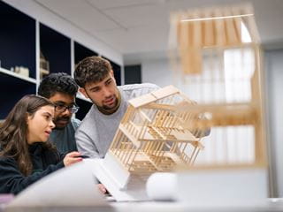 Three students examining a wooden model