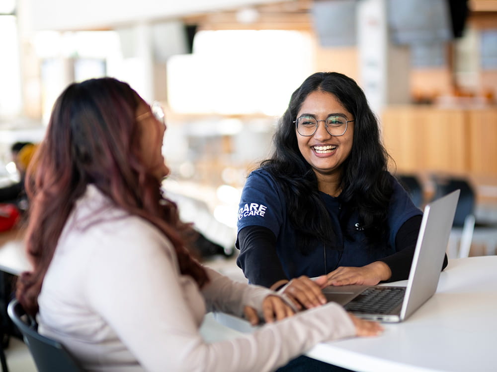 Two people laughing and smiling while seated in front of a laptop.