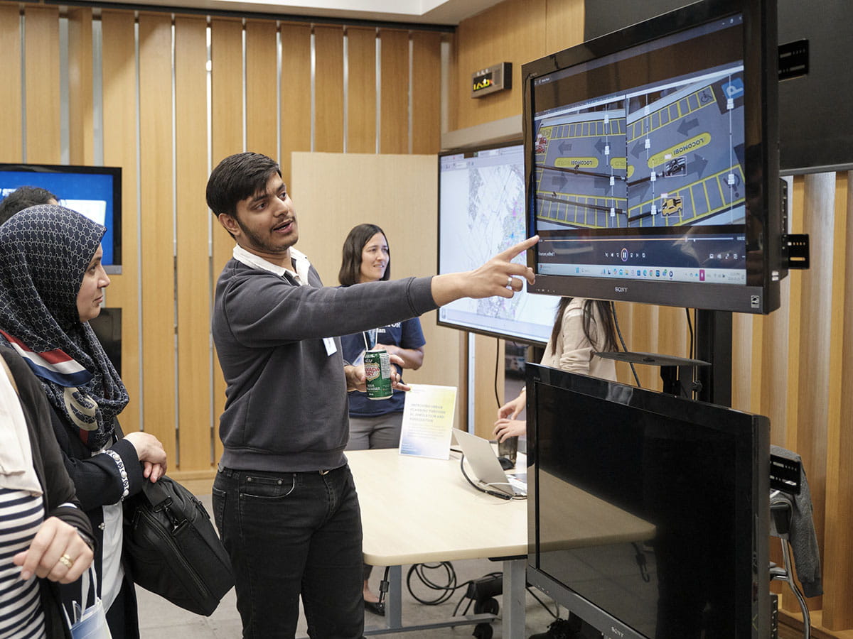 A person demonstrating something to another person using a monitor.