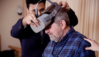 Person placing a VR headset onto another person's head