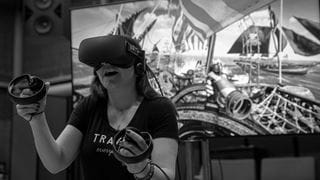 Person wearing a VR headset standing in front of a computer monitor