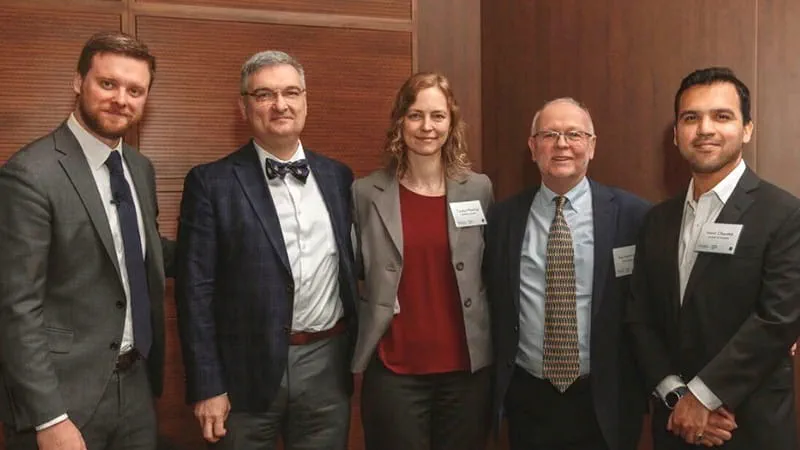 Five people standing in a line, posing for a photo