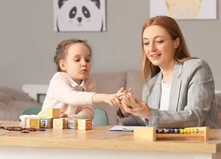 A behavioural specialist looking at alphabet blocks with a young child.