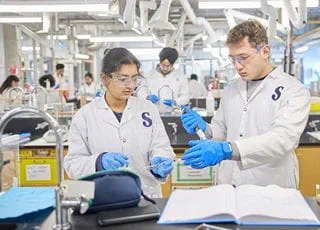 Two people wearing white lab coats and working in a biotechnology lab