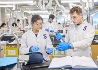 Two people wearing white lab coats and working in a biotechnology lab