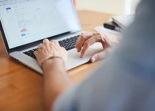 A person's hands typing on a laptop computer