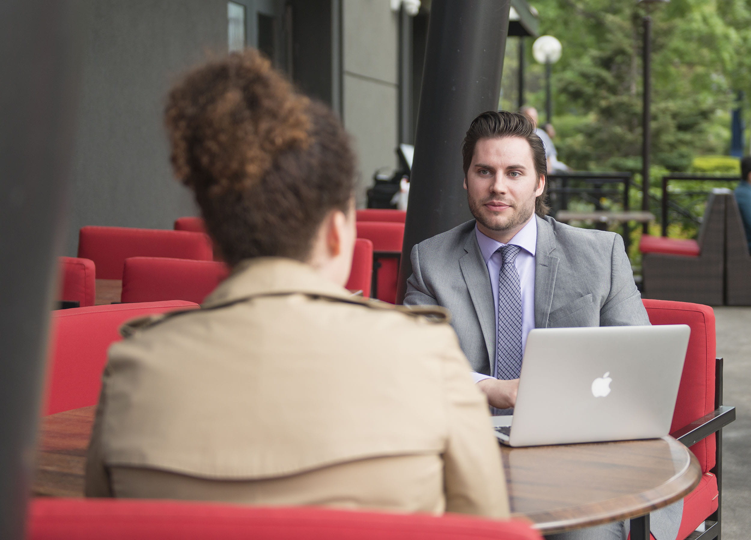 Two students in business attire sitting across from each other at a table on an outdoor patio