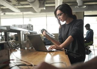 A young woman working with computer engineering technology in a lab space.