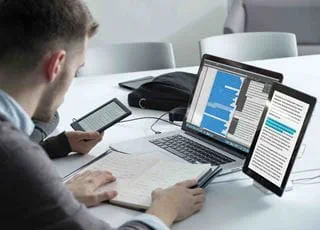 A student working on a laptop computer and tablet