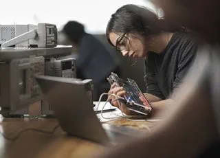 An electronics engineering technician student working in a lab