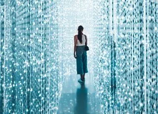 A woman standing on a small platform, surrounded by strings of blue and white lights running floor to ceiling.