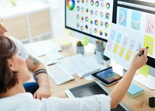 Students looking at graphic design treatments on computer monitors.