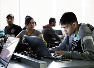 Interactive Media Management student working on a laptop