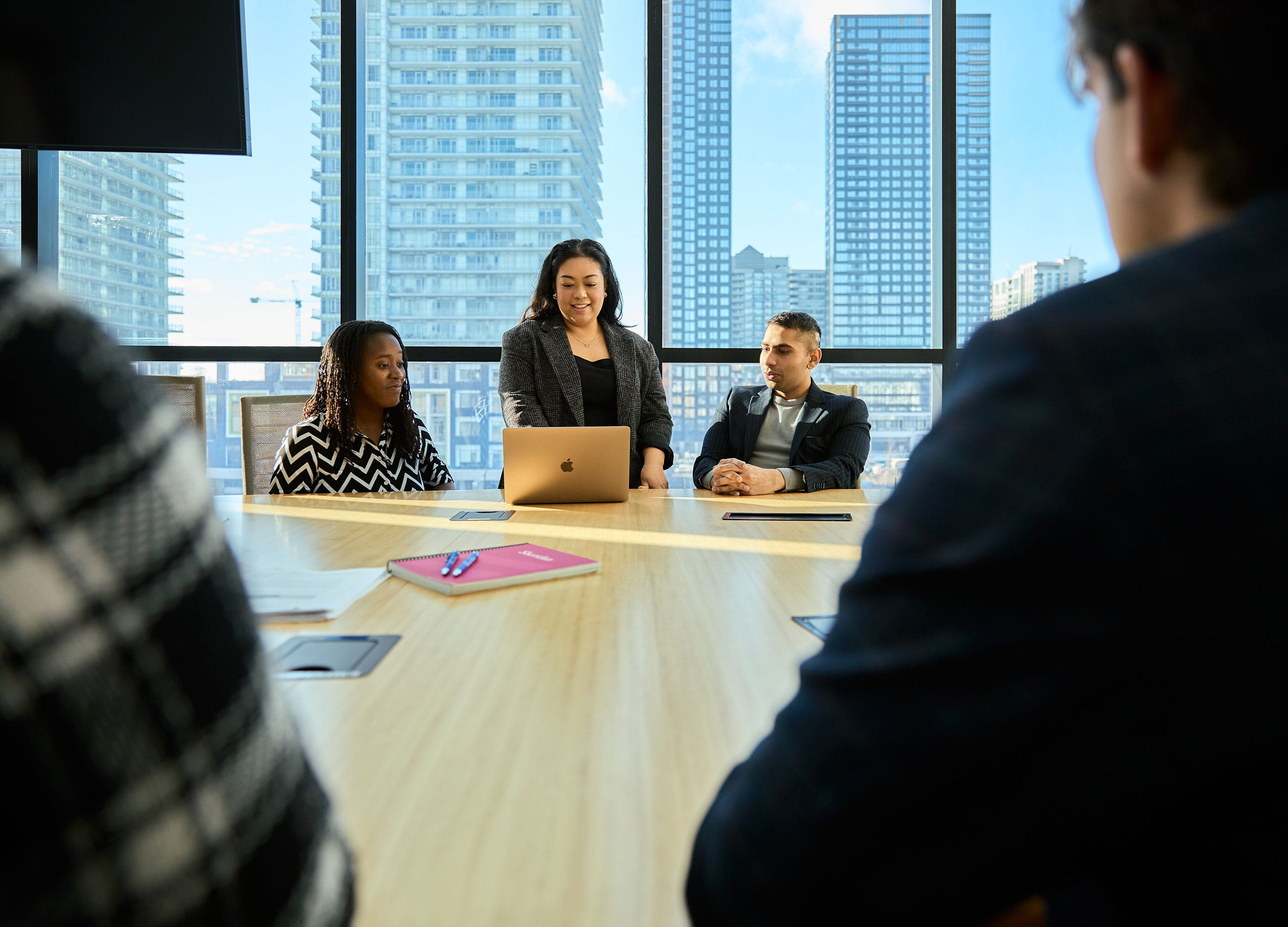 Three people in business attire looking at a laptop