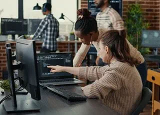 Two students looking at code on a shared computer screen.