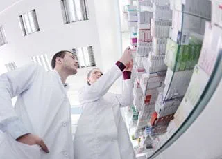 Pharmacy technicians looking at boxes of medication